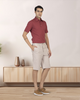 Model wearing custom Genoa shorts for men by Luxire in pale green wearing red top one hand in pocket