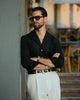 Male model wearing custom linen Gurkha pants for men by Luxire in cream arms crossed