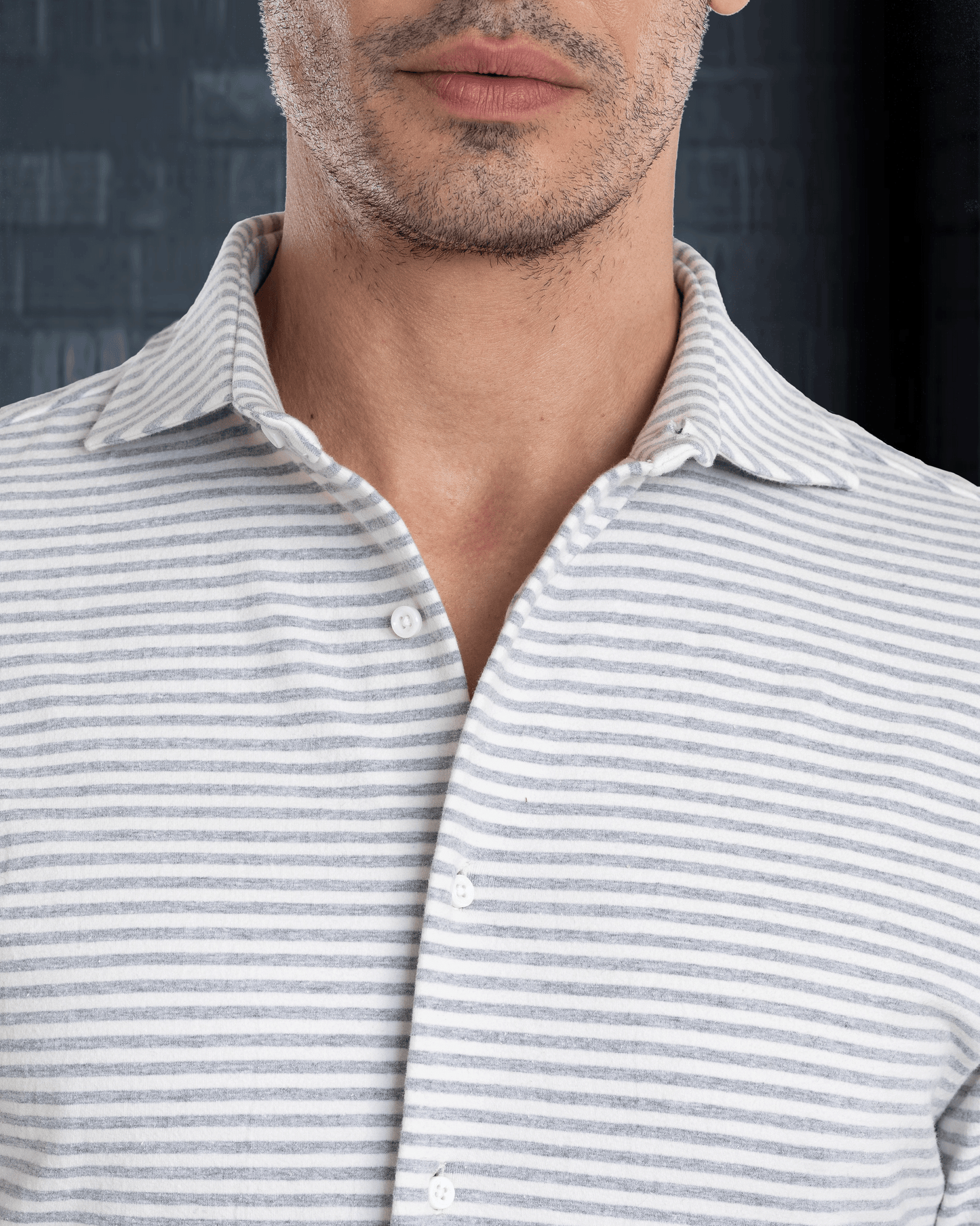 Close up of model wearing the custom oxford polo shirt for men by Luxire with grey and white candy stripes