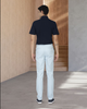 Back of model wearing the custom oxford polo shirt for men by Luxire in navy with white pants