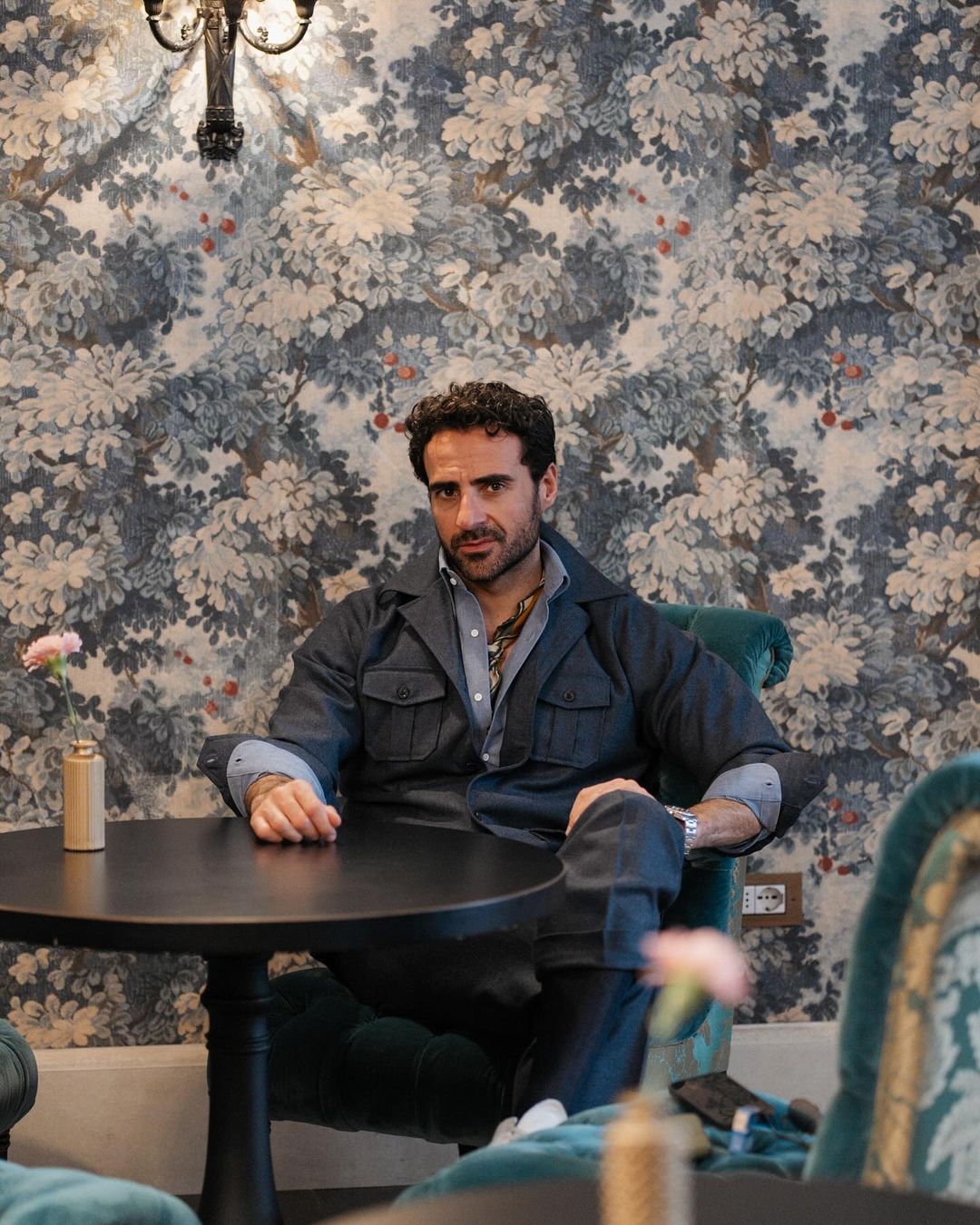 Model sitting at a table wearing the wool flannel shirt jacket for men by Luxire in navy blue