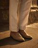 Pants and shoes of model outside wearing the safari jacket in linen cotton for men by Luxire in off white